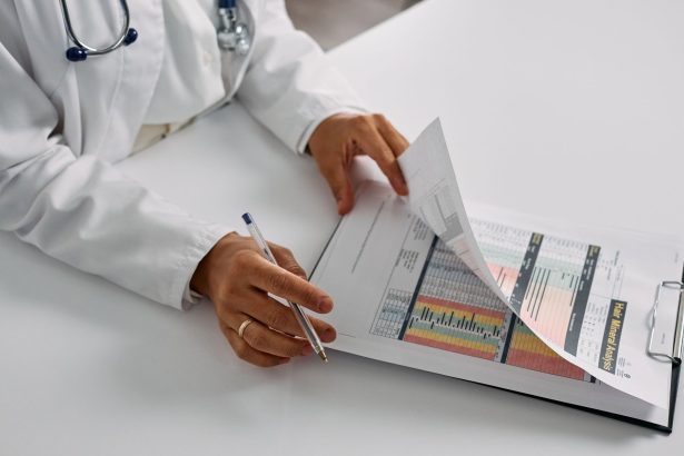 Profissional de saúde consulta relatórios em uma prancheta dentro de um escritório hospitalar.